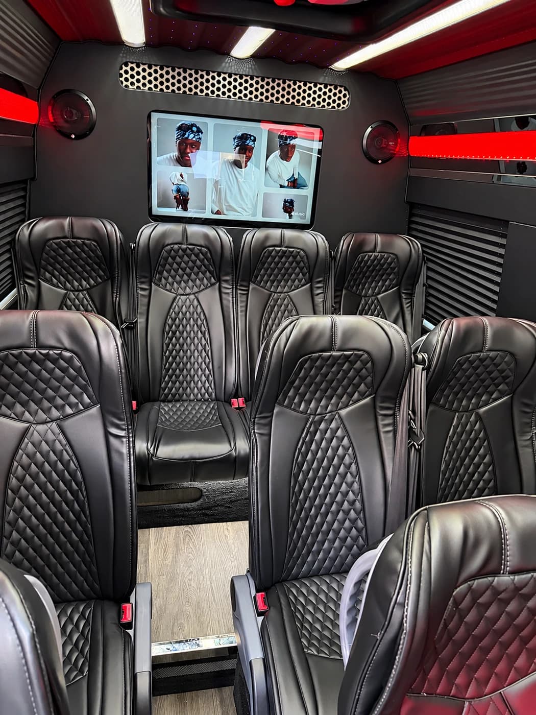 The Mercedes-Benz Executive Sprinter interior features black quilted leather seats, a rear screen, red lighting, and wood flooring.