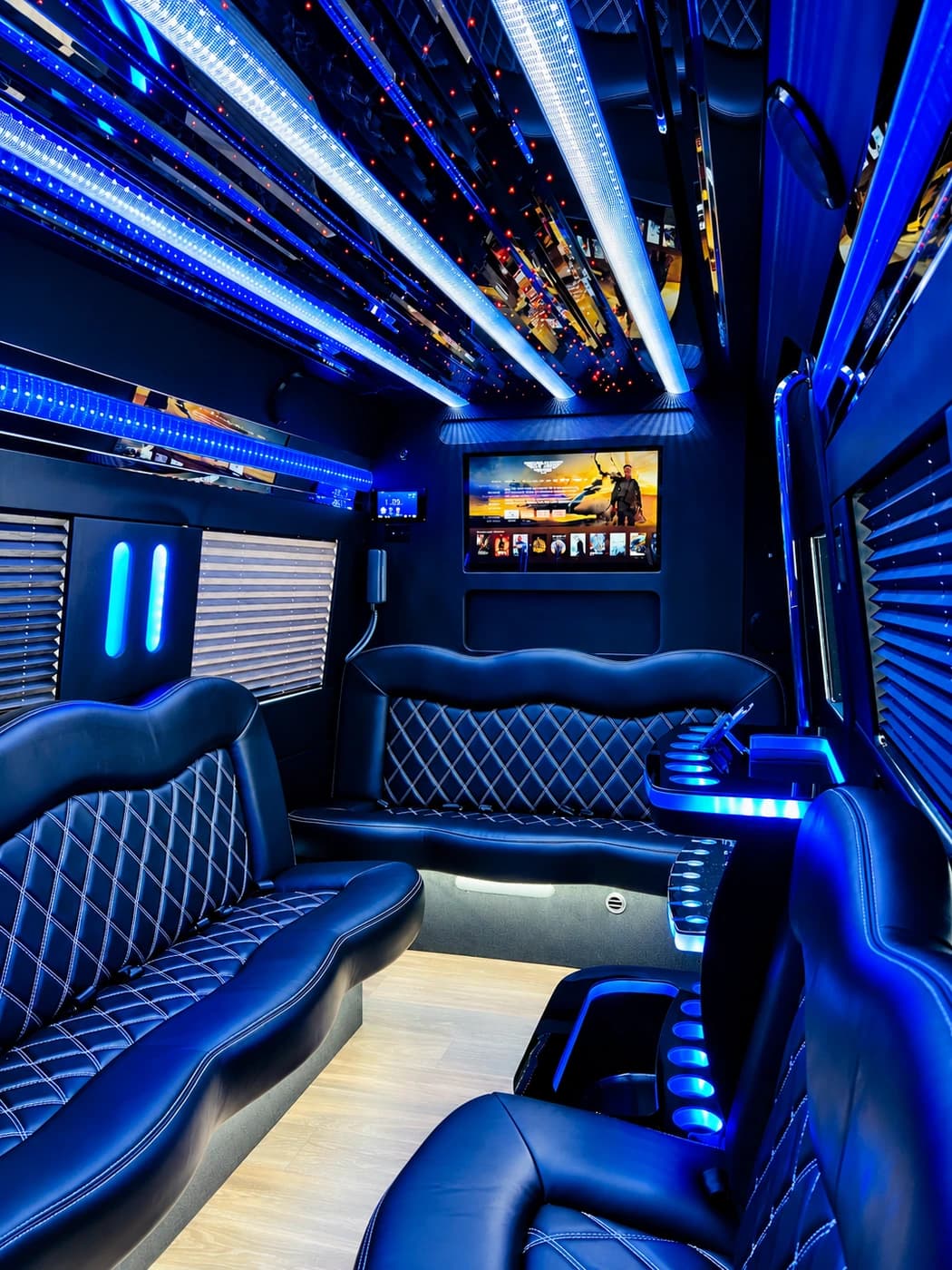 Mercedes-Benz Party Limo Sprinter with diamond-stitched black leather wraparound seating, blue LED lights, a mirrored ceiling and a TV.